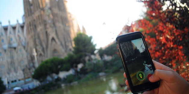 BARCELONA, SPAIN - JULY 15: In this photo illustration a young woman plays Pokemon GO in front of Sagrada Familia, on July 15, 2016 in Barcelona, Spain. (Photo by Joan Cros/Corbis via Getty Images)