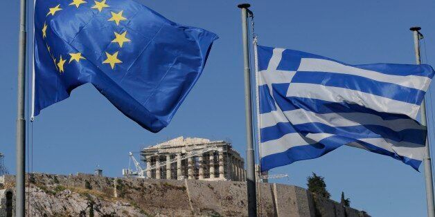 The Greek, right, and the European flags wave under the ancient Acropolis hill in Athens, Sunday, July 5, 2015. Greeks lined up at polling stations and ATMs alike Sunday as the country voted on its financial future, choosing in a referendum whether to accept creditors' demands for more austerity in return for rescue loans or defiantly reject the deal. (AP Photo/Petr David Josek)