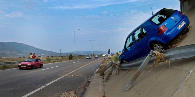 People take a picture of a car sent above the ringroad by the floods near the village of Stajkovci, near Skopje, on August 7, 2016. Fierce storms packing strong winds and torrential rains overnight killed at least 20 people in Macedonia's capital of Skopje, the health minister said August 7. The freak weather included winds blowing at more than 70 kilometres (43 miles) an hour and resulted in flash floods and landslides, with cars swept away by the violent torrents. / AFP / Robert ATANASOVSKI (Photo credit should read ROBERT ATANASOVSKI/AFP/Getty Images)