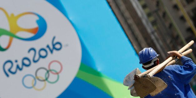 A construction worker walks by a logo of the Rio 2016 Olympics in Rio de Janeiro, Brazil, July 27, 2016. REUTERS/Kai Pfaffenbach
