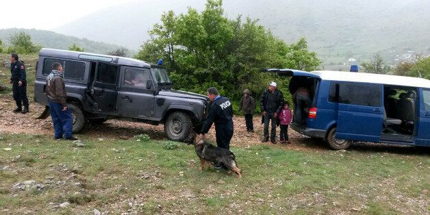 Albanian police officers detain Syrian migrants near the Albanian-Greek border near the city of Korca on May 4, 2016. / AFP / STRINGER (Photo credit should read STRINGER/AFP/Getty Images)
