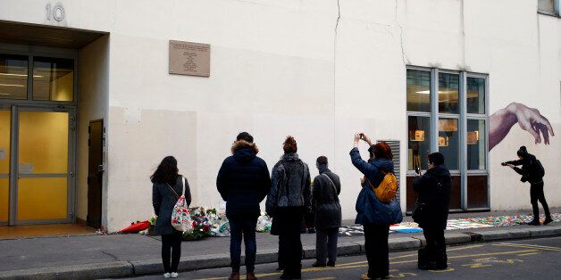 French onlookers gather outside satirical newspaper Charlie Hebdo former office, one year after the attacks on it, in Paris, France, Thursday, Jan. 7, 2016. It's a year to the day since an attack on the French satirical newspaper Charlie Hebdo launched a bloody year in the French capital. Tensions in France, under a state of emergency since a wave of attacks on Nov. 13, have been even higher this week as the anniversary of the January attacks approached. (AP Photo/Francois Mori)
