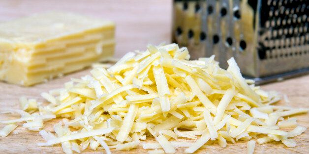 Grated cheese on chopping board with grater