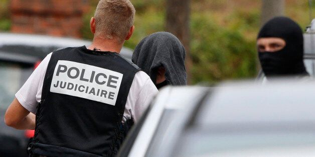 French judicial investigating police apprehends a man during a raid after a hostage-taking in the church in Saint-Etienne-du-Rouvray near Rouen in Normandy, France, July 26, 2016. A priest was killed with a knife and another hostage seriously wounded in an attack on a church that was carried out by assailants linked to Islamic State. REUTERS/Pascal Rossignol