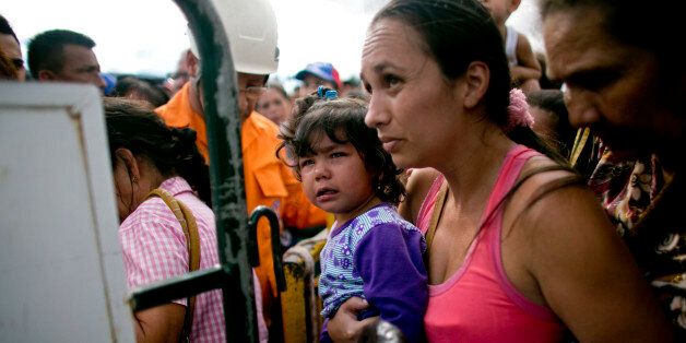 A woman carrying her daughter crosses into Colombia through the Simon Bolivar bridge in San Antonio del Tachira, Venezuela, Sunday July 17, 2016. Tens of thousands of Venezuelans crossed the border into Colombia on Sunday to hunt for food and medicine that are in short supply at home. It's the second weekend in a row that Venezuelaâs government has opened the long-closed border connecting Venezuela to Colombia. (AP Photo/Ariana Cubillos)