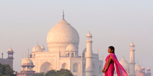 Young Indian woman walking near Taj Mahal in early morning light.