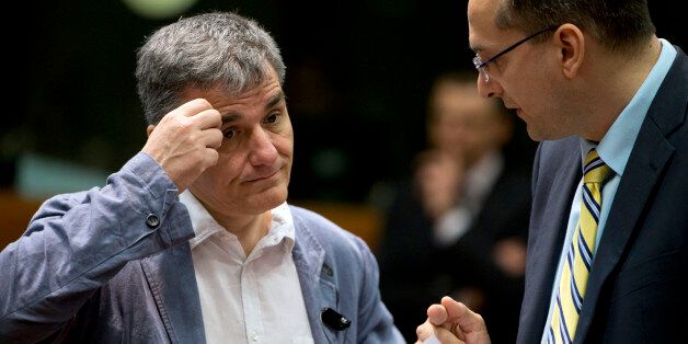 Greece's Finance Minister Eucleidis Tsakalotos, left, speaks with a member of his delegation during a meeting of EU finance ministers in Brussels on Wednesday, May 25, 2016. Eurozone finance ministers struck a deal early Wednesday clearing the way for Greece to access a fresh round of bailout funds, while also laying out debt relief measures aimed at securing the involvement of the International Monetary Fund, or IMF. (AP Photo/Virginia Mayo)