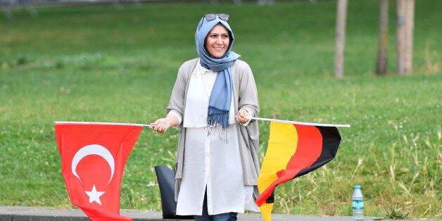 A Turkish woman holding a Turkish and a German flag waits for the start of a demonstration in Cologne, Germany, Sunday, July 31, 2016. Supporters of Turkish President Recep Tayyip Erdogan are expected to demonstrate in Cologne amid heavy police presence. Some 30,000 participants are expected at Sunday's demonstration, which comes amid tensions following the failed coup attempt in Turkey and concern in Germany over the extent of the Turkish government's subsequent crackdown. (AP Photo/Martin Meis