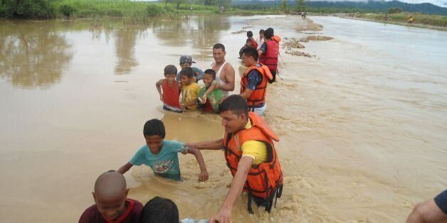 In this photograph taken on June 26, 2016, Nepalese Police personnel guide children through floodwaters at Babai Muinicipality-7 in Bardiya, some 400 kms southwest of Kathmandu. At least 33 people have died in floods and landslides triggered by heavy rains in Nepal and dozens more are missing, a government official said July 27. / AFP / Kamal Panthi (Photo credit should read KAMAL PANTHI/AFP/Getty Images)