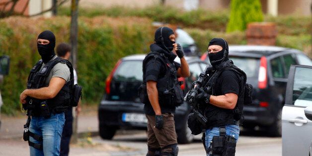 Police officers conduct a search in Saint-Etienne-du-Rouvray, Normandy, France, following an attack on a church that left a priest dead, Tuesday, July 26, 2016. Two attackers invaded a church Tuesday during morning Mass near the Normandy city of Rouen, killing an 84-year-old priest by slitting his throat and taking hostages before being shot and killed by police, French officials said. (AP Photo/Francois Mori)