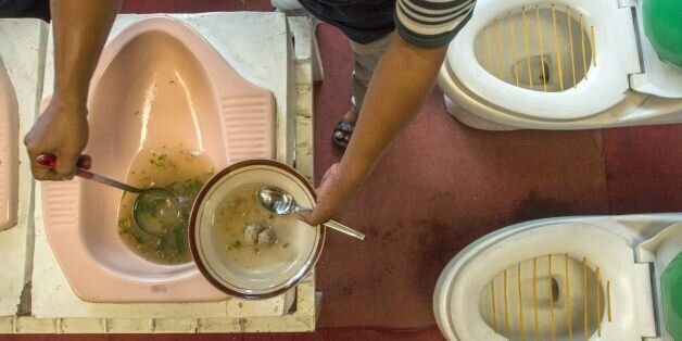 This picture taken on July 16, 2016 shows customers being served meatball soup from a squat toilet during a meal at the 'Jamban Cafe' in the city of Semarang on Java island, a small eatery where a handful of diners sit on upright toilets around a table where food is served in two squat toilets.The toilet-themed cafe where customers dine on meatballs floating in soup-filled latrines may not be everyone's idea of haute cuisine, but Indonesians are flocking to become privy to the latest lavatorial trend. / AFP / SURYO WIBOWO (Photo credit should read SURYO WIBOWO/AFP/Getty Images)