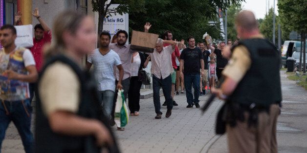 Police escort people who leave the Olympia mall in Munich, southern Germany, Friday, July 22, 2016 after shots were fired. Police said that at least six people have been killed. (AP Photo/Sebastian Widmann)