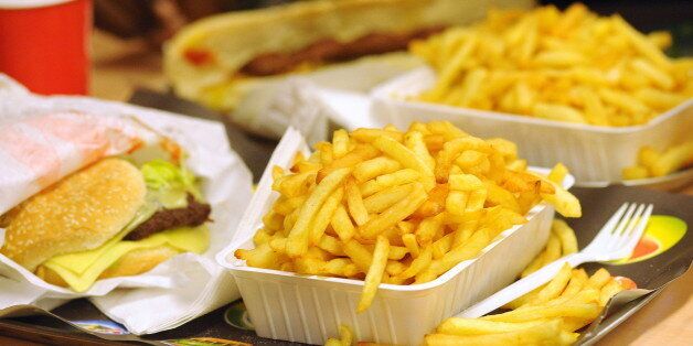Chip shop, chips / fries in a cardboard tray and hamburger in a chip shop. Fatty foods; calorie; fast-food; fast cooking; trade; paper cone of chips (Photo by: Andia/UIG via Getty Images)