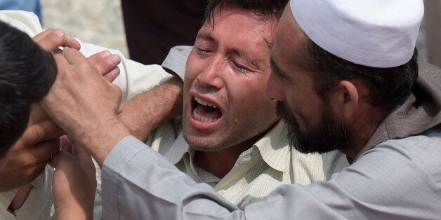 A relative (C) is comforted as he weeps alongside unseen shoes and other belongings of those who were killed in the twin suicide attack, at a mosque in Kabul on July 24, 2016Islamic State jihadists claimed responsibility for twin explosions on July 23 that ripped through crowds of Shiite Hazaras in Kabul, killing at least 80 people and wounding 231 others in the deadliest attack in the Afghan capital since 2001. / AFP / SHAH MARAI (Photo credit should read SHAH MARAI/AFP/Getty Images)