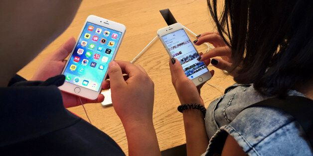 Customers try out Apple iPhone 6S models on display at an Apple Store in Beijing, Saturday, June 18, 2016. A Chinese regulator has ordered Apple Inc. to stop selling two versions of its iPhone 6 in the city of Beijing after finding it looks too much like a competitor, but Apple says sales are going ahead while it appeals. (AP Photo/Mark Schiefelbein)