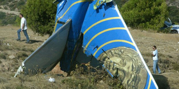 Police officers walk behind the tail of the crashed Cypriot Helios plane on a hillside in Grammatiko,...