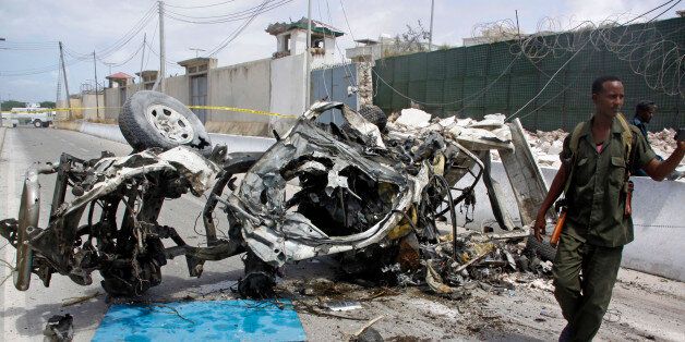 Somali soldier stand near the wreckage of a car bomb outside the UN's office in Mogadishu, Somalia, Tuesday,...