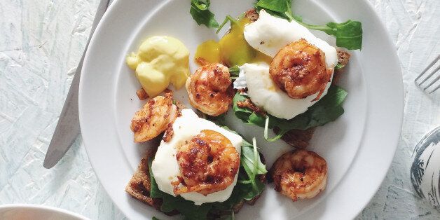 Poached eggs on sourdough bread with chilli prawns and rocket