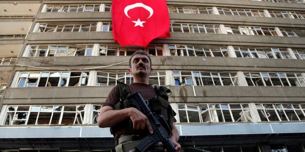 A Turkish special forces policeman stands guard in front of a damaged building inside the special forces policemen base which was attacked by the Turkish warplanes during the failed military coup last Friday, in Ankara, Turkey, Tuesday, July 19, 2016. The violence surrounding the Friday night coup attempt claimed the lives of 208 government supporters and 24 coup plotters, according to the government. Turkey says Fethullah Gulen, a U.S.-based Muslim cleric, was behind the coup and has demanded his extradition. Gulen has denied any knowledge of the failed coup. (AP Photo/Hussein Malla)