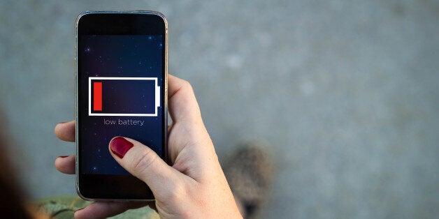 Top view of woman walking in the street using her mobile phone with low battery on screen with copyspace. All screen graphics are made up.