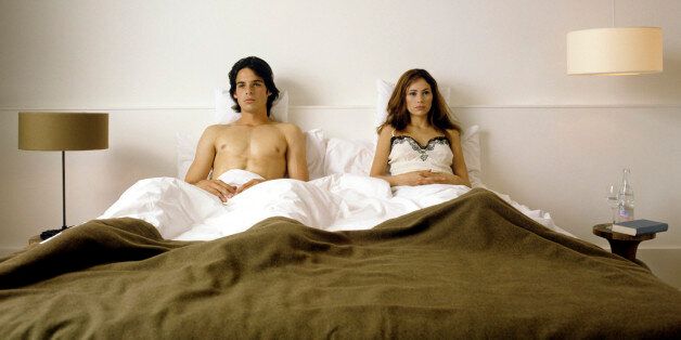 serious looking couple lying together in bed