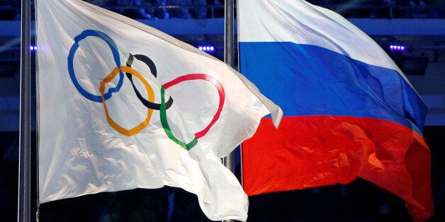 The Russian national flag (R) and the Olympic flag are seen during the closing ceremony for the 2014 Sochi Winter Olympics, Russia, February 23, 2014. REUTERS/Jim Young/File Photo