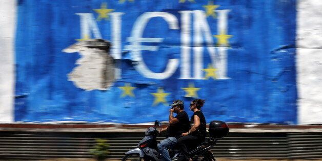 People ride past graffiti in Athens, Greece July 12, 2015. Euro zone leaders will fight to the finish to keep near-bankrupt Greece in the euro zone on Sunday after the European Union's chairman cancelled a planned summit of all 28 EU leaders that would have been needed in case of a