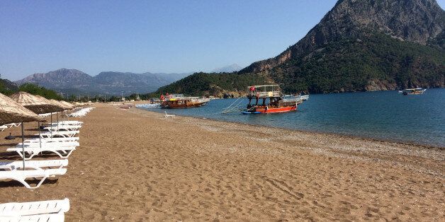 FILE - In this June 1, 2016 file photo, boats wait for tourists in Adrasan in Olympos area, about 100 kilometers west of Antalya, Turkey. Turkey's state-run news agency says authorities are evacuating residents and tourists from Olimpos village, 7 kilometers from behind the mountain in this picture, that is threatened by a forest fire. Anadolu Agency says the fire which broke out near the resort of Adrasan on Sunday was spreading toward the nearby retreat of Olimpos, fanned by winds.(AP Photo/Burhan Ozbilici, FILE)