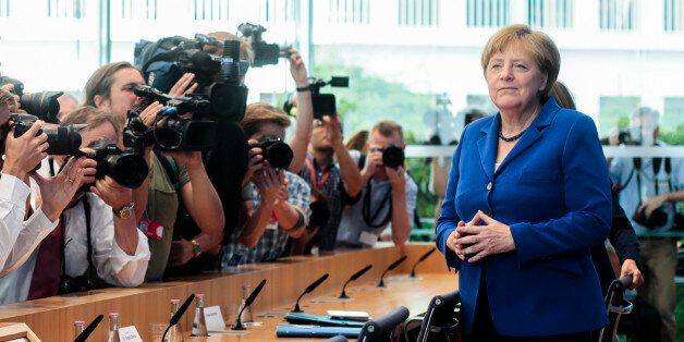 German Chancellor Angela Merkel, right, arrives for a news conference in Berlin Thursday, July 28, 2016. Chancellor Angela Merkel says the fact that two men who came to Germany as refugees carried out attacks claimed by the Islamic State group