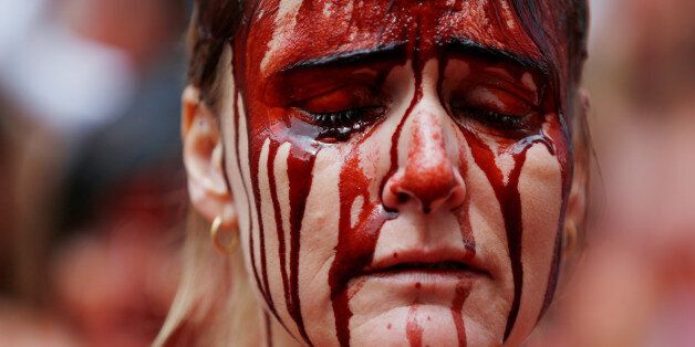 An animal rights protester covered in fake blood reacts during a demonstration for the abolition of bull runs and bullfights a day before the start of the famous running of the bulls San Fermin festival in Pamplona, northern Spain, July 5, 2016. REUTERS/Susana Vera