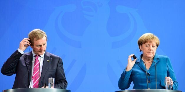 German Chancellor Angela Merkel (R) and Irish Prime Minister Enda Kenny use their earpieces as they address a joint news conference at the chancellery in Berlin on July 12, 2016. / AFP / John MACDOUGALL (Photo credit should read JOHN MACDOUGALL/AFP/Getty Images)