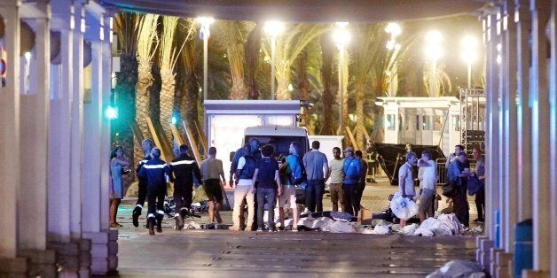 People stand next to covered bodies in the early hours of Friday, July 15, 2016, on the Promenade des Anglais in Nice, southern France. France has been stunned again as a large white truck killed many people after it mowed through a crowd of revelers gathered for a Bastille Day fireworks display late Thursday evening, in the Riviera city of Nice. (AP Photo)