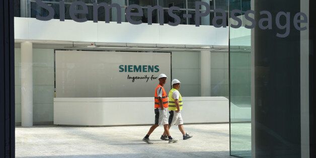 Workers walk in the main entrance hall of the new headquarters of the German engineering giant Siemens in Munich, southern Germany, on June 14, 2016.The new building designed and built in the past six years, will provide jobs for 1,200 employees and will be officially opened at the end of June 2016. / AFP / CHRISTOF STACHE (Photo credit should read CHRISTOF STACHE/AFP/Getty Images)