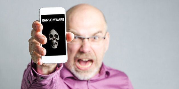 Angry man showing his mobile phone with virus attack by ransomware , studio shot on grey background