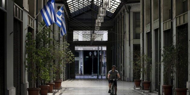 A man cycles through a shopping arcade where the vast majority of its shops have closed due to financial problems in the last four years in Athens, Greece, July 12, 2015. Euro zone leaders will fight to the finish to keep near-bankrupt Greece in the euro zone on Sunday after the European Union's chairman cancelled a planned summit of all 28 EU leaders that would have been needed in case of a