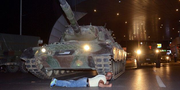 A man lays in front of a tank in the entrance to Istanbul's Ataturk airport, early Saturday, July 16, 2016. Members of Turkey's armed forces said they had taken control of the country, but Turkish officials said the coup attempt had been repelled early Saturday morning in a night of violence, according to state-run media. (Ismail Coskun/IHA via AP)