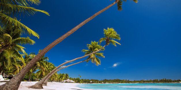 Few palm trees over stunning tropical lagoon with white beach