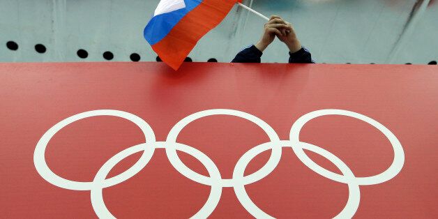 FILE - In this Feb. 18, 2014, file photo, a Russian skating fan holds the country's national flag over the Olympic rings before the start of the men's 10,000-meter speedskating race at Adler Arena Skating Center during the 2014 Winter Olympics in Sochi, Russia. On Monday, July 18, 2016 WADA investigator Richard McLaren confirmed claims of state-run doping in Russia. (AP Photo/David J. Phillip, File)