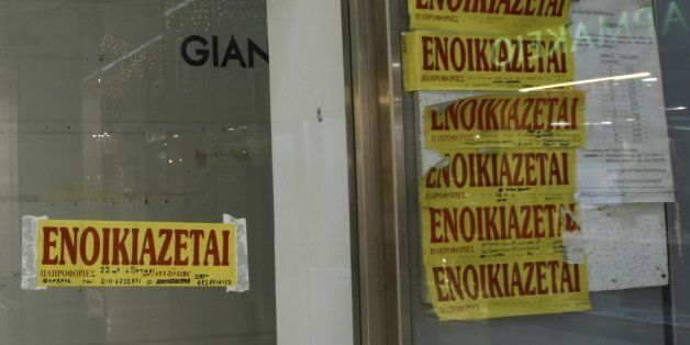 People walk outside empty stores with rental signs posted on glass windows in central Athens December 22, 2009. Moody's cut the debt ratings of several Greek lenders on concerns about their profitability amid a slowing economy and the government's reduced ability to support them, after cutting Greece's sovereign debt earlier on Tuesday.REUTERS/Yiorgos Karahalis (GREECE - Tags: SOCIETY BUSINESS EMPLOYMENT)