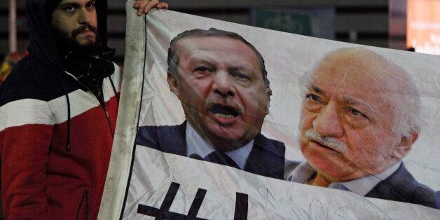 A demonstrator hold pictures of Turkey's Prime Minister Tayyip Erdogan and Turkish cleric Fethullah Gulen (R), during a protest against Turkey's ruling AK Party (AKP), demanding the resignation of Erdogan, in Istanbul December 30, 2013. Erdogan swore on Sunday he would survive a corruption crisis circling his cabinet, saying those seeking his overthrow would fail just like mass anti-government protests last summer. Gulen denies involvement in stirring up the graft case, but he regularly censures Erdogan, a ex-ally with whom he fell out in a dispute for control over an influential network of Turkish cram schools. REUTERS/Osman Orsal (TURKEY - Tags: POLITICS CRIME LAW CIVIL UNREST)