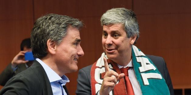 Greek Finance Minister Euclid Tsakalotos talks with Portuguese Finance Minister Mario Centeno (R) wearing the soccer national team scarf during an Eurogroup meeting at the EU headquarters in Brussels on July 11, 2016 one day after Portugal won the Euro 2016 final football match against France in Paris. / AFP / JOHN THYS (Photo credit should read JOHN THYS/AFP/Getty Images)