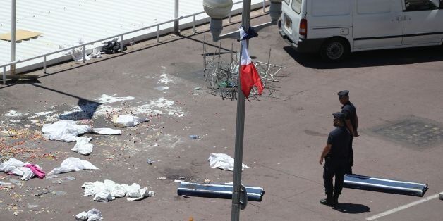 French gendarmes stand next to a French flag at half-staff and debris at the site of the deadly attack on the Promenade des Anglais seafront in the French Riviera city of Nice on July 15, 2016, after a gunman smashed a truck through a crowd celebrating Bastille Day, killing at least 84 and injuring dozens of children in what President Francois Hollande called a 'terrorist' attack.Hollande declared three days of mourning after the assault, as the shellshocked country found itself again mourning its dead after attacks on Charlie Hebdo magazine in January 2015 and the November 2015 massacre in Paris. / AFP / Valery HACHE (Photo credit should read VALERY HACHE/AFP/Getty Images)