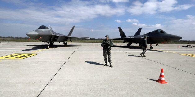 U.S. Army soldiers guard as U.S. Air Force F-22 Raptor fighters are parked in the military air base in Siauliai, Lithuania, April 27, 2016. REUTERS/Ints Kalnins