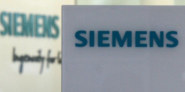 A worker passes by the logo of German engineering giant Siemens at it new headquarter in Munich, southern Germany, on June 14, 2016.The new building was designed and built in the past six years, provides future jobs for 1,200 employees and will be officially opened at the end of June 2016. / AFP / CHRISTOF STACHE (Photo credit should read CHRISTOF STACHE/AFP/Getty Images)