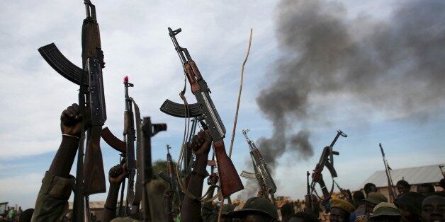 Rebel fighters hold up their rifles as they walk in front of a bushfire in a rebel-controlled territory in Upper Nile State, South Sudan February 13, 2014. REUTERS/Goran Tomasevic/File Photo