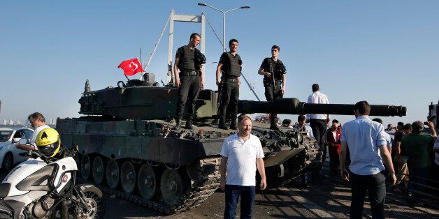 People gather around as Turkish police officers, loyal to the government, stand atop tanks abandoned by Turkish army officers, backdropped by Istanbul's iconic Bosporus Bridge, Saturday, July 16, 2016. Turkish President Recep Tayyip Erdogan declared he was in control of the country early Saturday as government forces fought to squash a coup attempt during a night of explosions, air battles and gunfire that left dozens dead. (AP Photo/Emrah Gurel)