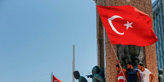 People protesting against the coup, wave a Turkish flag on top of the monument in Taksim square, Istanbul, Turkey, Saturday, July 16, 2016. Turkish President Recep Tayyip Erdogan told the nation Saturday that his government is in charge after a coup attempt brought a night of explosions, air battles and gunfire across the capital that left dozens dead. The state-run news agency said more than 750 soldiers have been detained across the country. (AP Photo/Emrah Gurel)