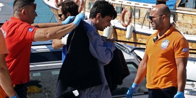 Paramedics escort refugees after being rescued at the port of Mytilene on the island of Lesbos on July 13, 2016. The bodies of four migrants -- including two children -- were pulled from the Aegean Sea on July 13 after their boat sank off the Greek island of Lesbos, port police said. Coastguard rescuers saved six other people, while another person is still missing from the group of 11 that set off for Greece from the Turkish coast. / AFP / STR (Photo credit should read STR/AFP/Getty Images)