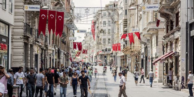Banners of the Turkish national flag hang above pedestrians passing along a half empty Taksim street in Istanbul, Turkey, on Monday, July 18, 2016. Tourism is an essential source of foreign currency to finance Turkey's current-account deficit and employs 8 percent of the nation's workforce. Photographer: Ismail Ferdous/Bloomberg via Getty Images
