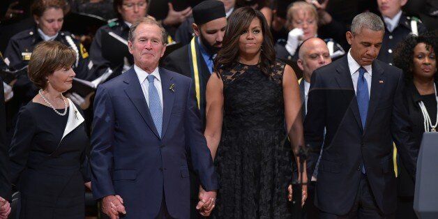 TOPSHOT - L-R: Former first lady Laura Bush, former US president George W. Bush, US First Lady Michelle Obama and US President Barack Obama join hands during the singing of 'The Battle Hymn of the Republic' during an interfaith memorial service for the victims of the Dallas police shooting at the Morton H. Meyerson Symphony Center on July 12, 2016 in Dallas, Texas.President Barack Obama attended a somber memorial Tuesday to five police officers slain in a sniper ambush in Dallas, as he seeks to unify a country divided by race and politics. / AFP / MANDEL NGAN (Photo credit should read MANDEL NGAN/AFP/Getty Images)